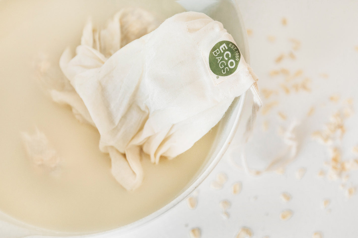 White cloth cotton nut milk bag with 'Eco Bags' label in a bowl of liquid