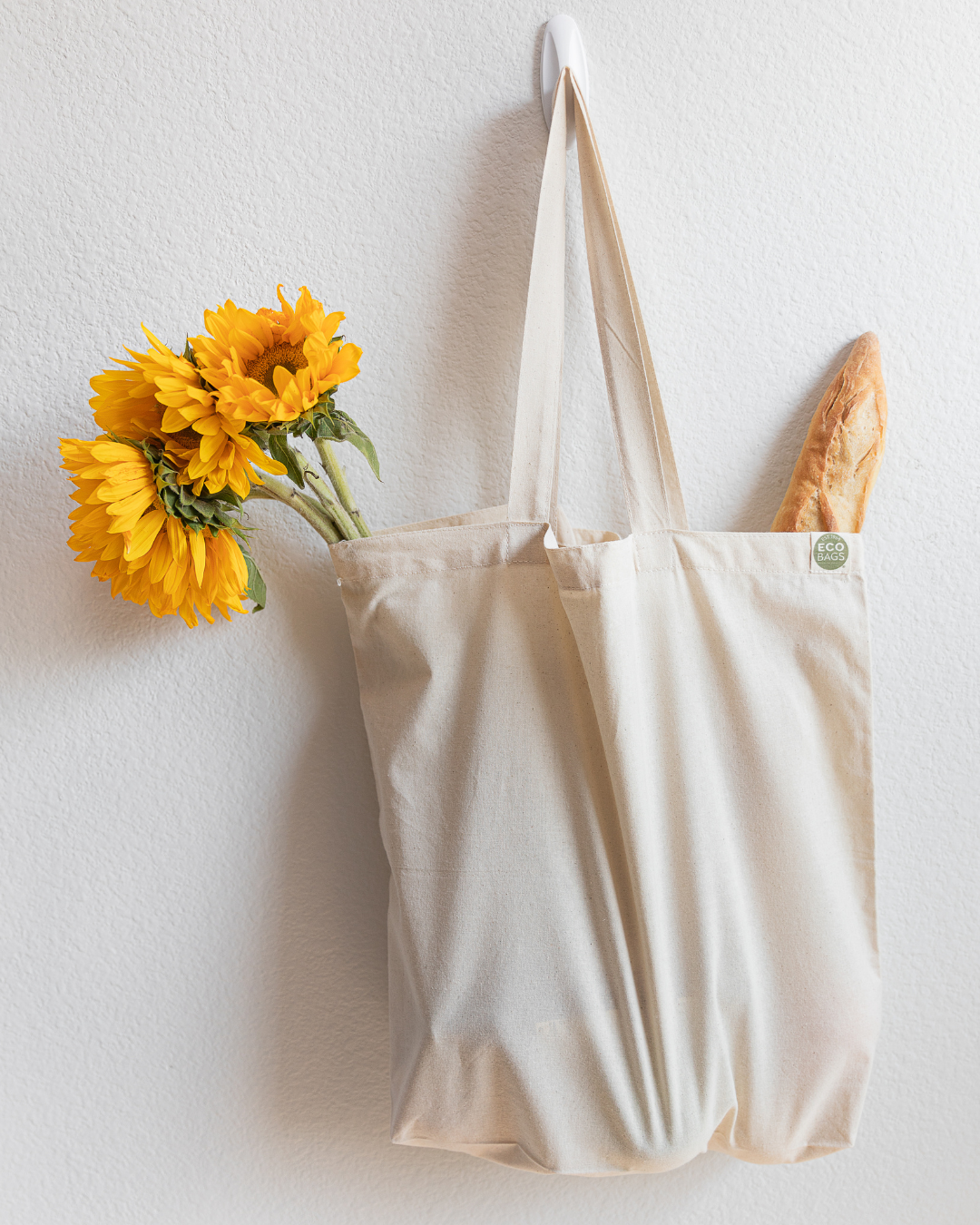 Beige natural tote bag with sunflowers and bread on a white background
