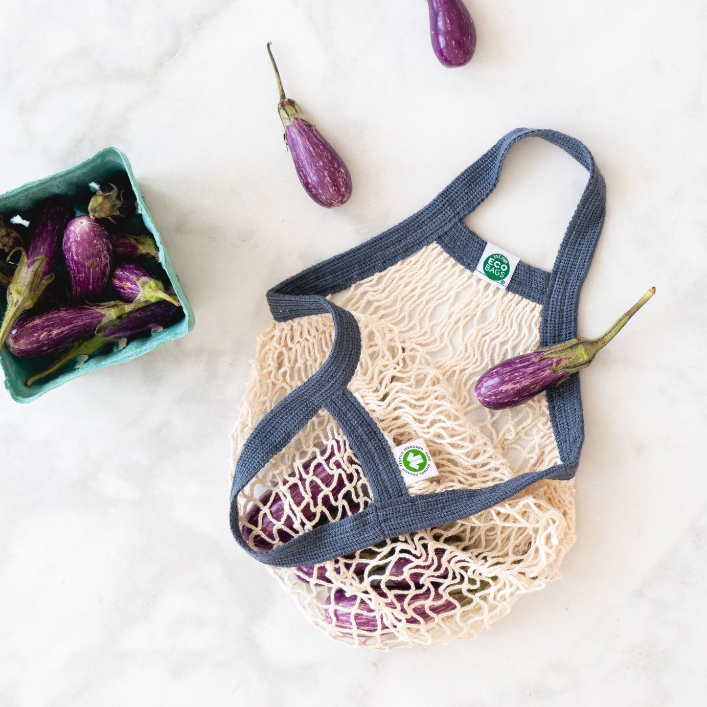 ECOBAGS Mini String Bag in natural and Storm Blue containing small purple eggplants