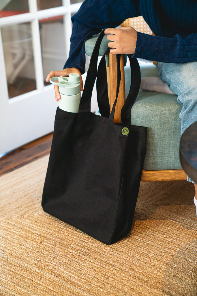 A person pulls a water bottle out of their black tote bag